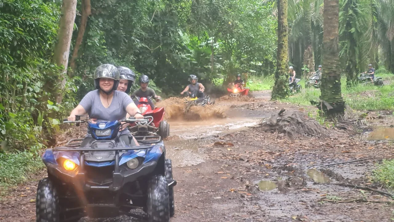 Traveler riding an ATV through a muddy palm trail